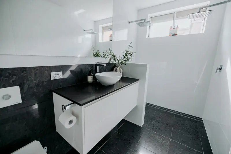 Modern bathroom with dark stone vanity top, vessel basin, and walk-in shower.