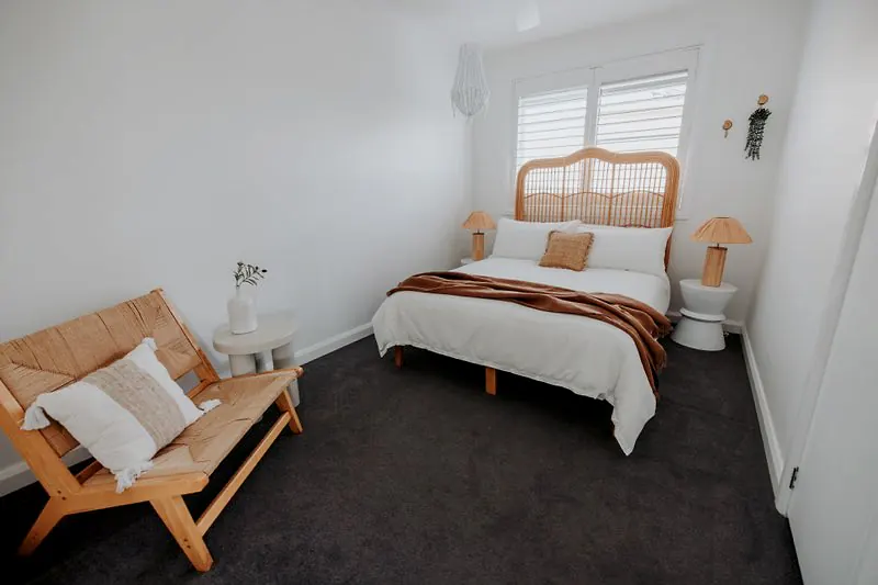 Bedroom with cane headboard, neutral tones, and minimalist furniture.