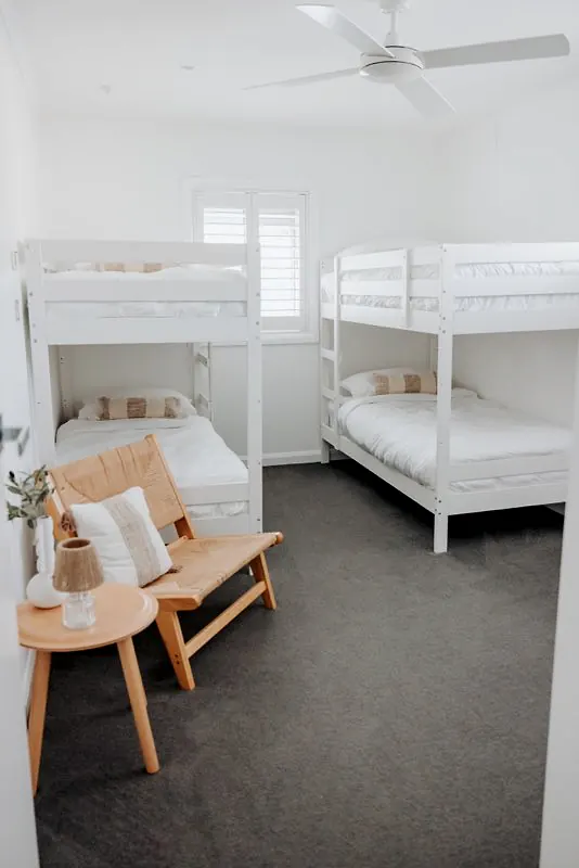 Bunk room with four beds, soft furnishings, and bright natural light.