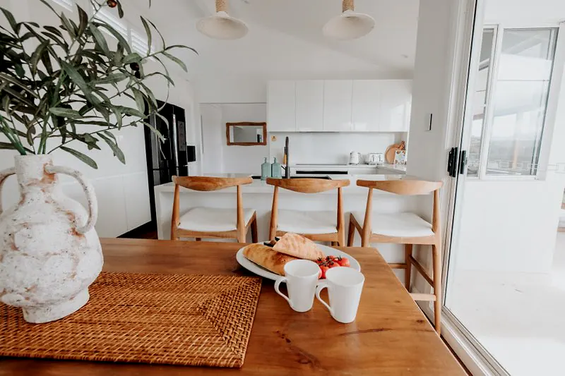 Styled timber dining table looking through to the bright kitchen and breakfast bar.