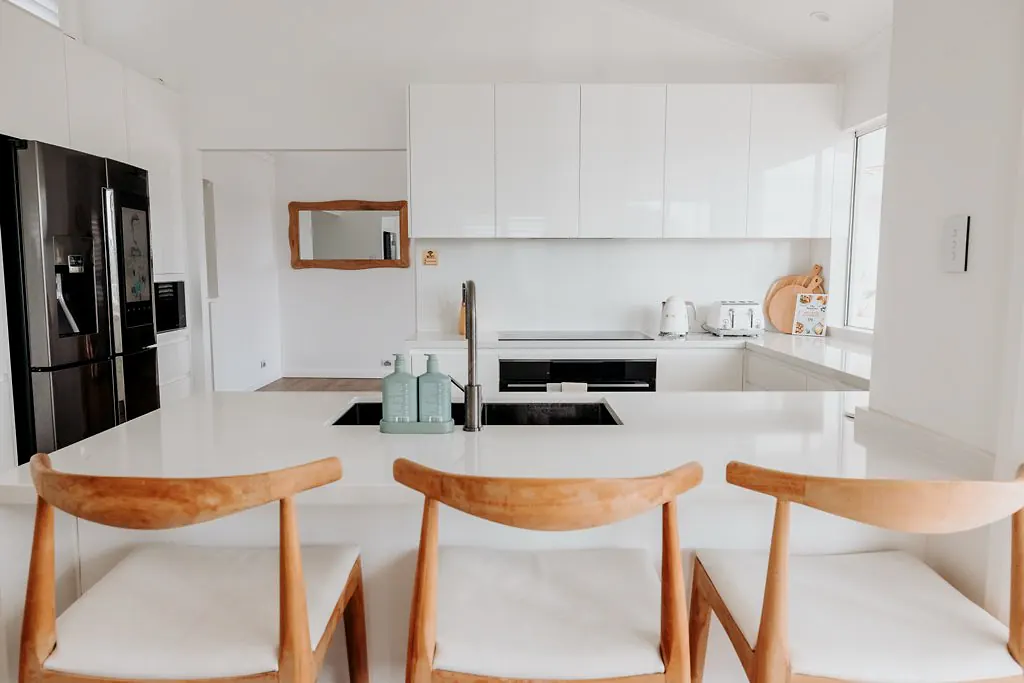 Clean white kitchen with island seating and minimalist styling.