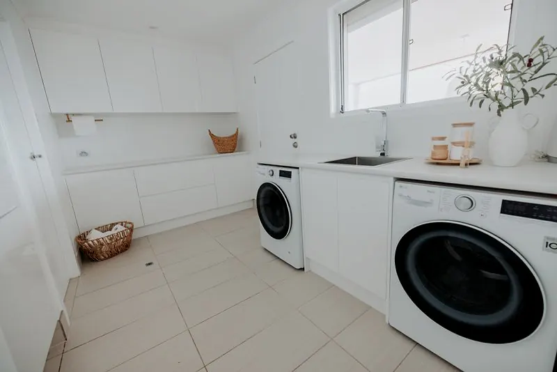 Clean laundry room with built-in cabinetry, washer, dryer, and sink.