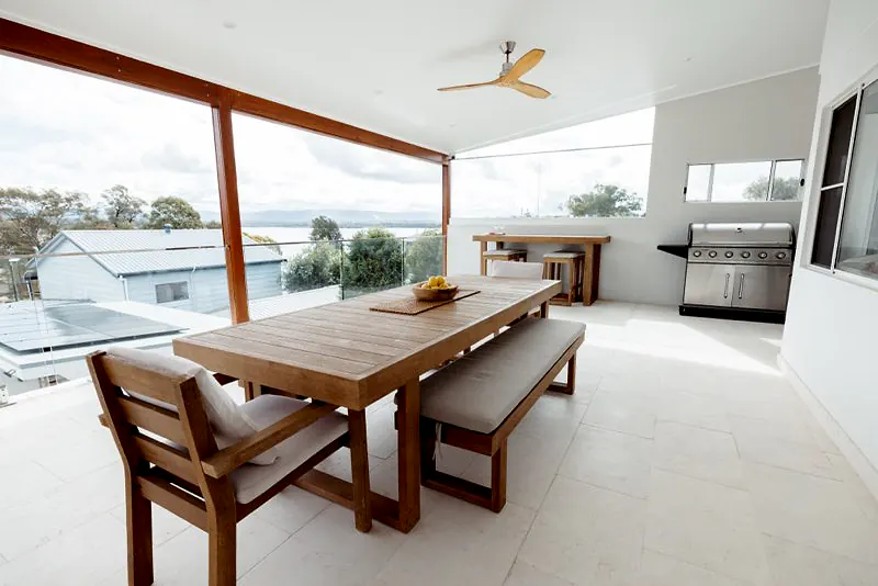 Covered outdoor dining area with barbecue and elevated water views.