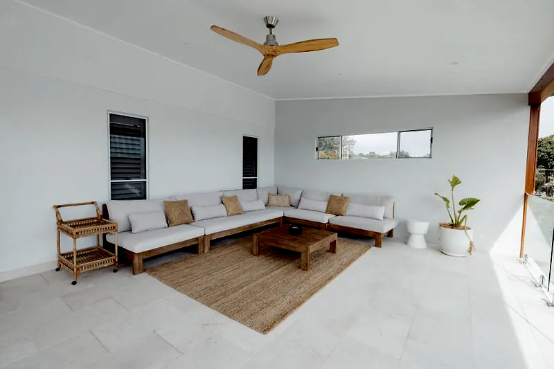 Covered outdoor lounge area with timber seating and a neutral rug.