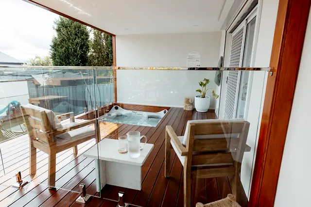 Timber spa deck with seating area and glass balustrade.